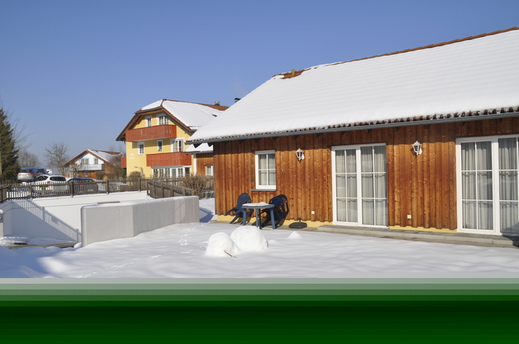Holzhaus im Schnee mit klarem blauen Himmel im Hintergrund.