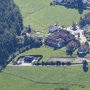 Luftaufnahme eines grünen, ländlichen Gebiets mit Gebäuden und Wald.