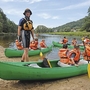 Menschen in Schwimmwesten bereiten sich auf eine Kanufahrt auf einem Fluss vor.