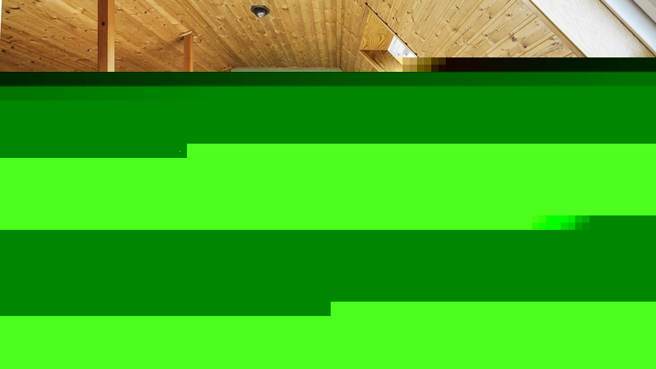Dachzimmer mit zwei Betten und Holzverkleidung in Ferienanlage.