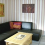 Wohnzimmer mit schwarzem Ledersofa, Holztisch und gestreifter Tapete.
