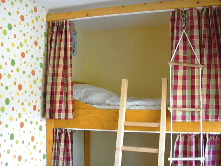 Hochbett mit Leiter und Vorhängen in einem Kinderzimmer.