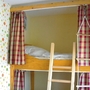 Hochbett mit Leiter und Vorhängen in einem Kinderzimmer.