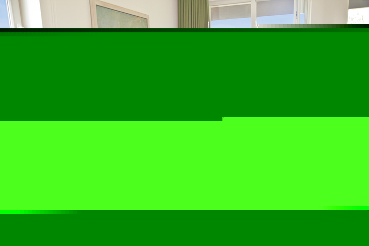 Wohnzimmer mit Sofa, Couchtisch und Blick auf Balkon; Urlaub in Ferienwohnung.