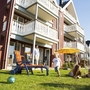 Familie entspannt auf der Wiese vor Ferienhäusern im Ferienpark Müritz.
