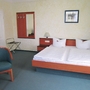 Hotelzimmer mit Doppelbett, zwei Nachttischen, Stuhl und Spiegel.
