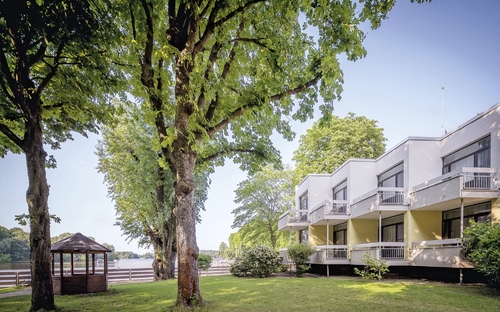 Außenansicht des Seehotel Grunewald mit Bäumen und Gartenanlage.