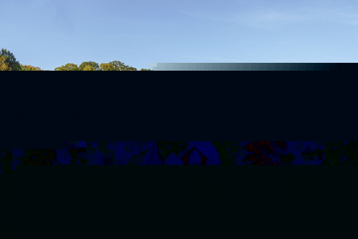 Segelboot auf dem Wannsee vor buntem Herbstwald und Bootshaus.