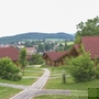 Ferienhäuser in einer grünen Landschaft mit Blick auf Hügel und Ort im Hintergrund.
