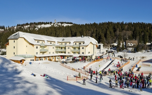 Skigebiet mit Hotel und Skifahrern im verschneiten Schwarzwald, Feldberg.