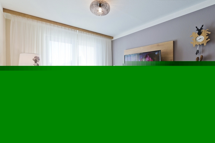 Modernes Wohnzimmer mit Sofa, Fernseher und dekorativer Lampe.