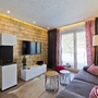 Modernes Wohnzimmer mit grauem Sofa, TV, Holzverkleidung und Fenstertüren.