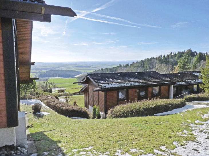 Ferienhäuser im Grünen mit Ausblick auf hügelige Landschaft und Wald.