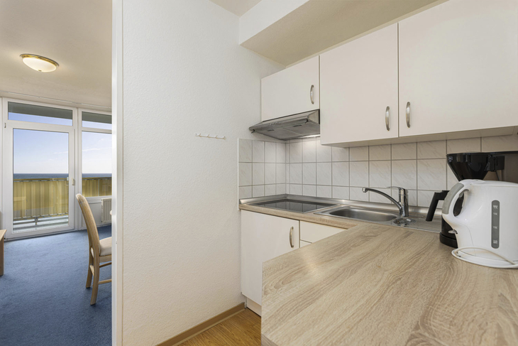 Kleine Küche in Ferienwohnung mit Esstisch und Balkonzugang.