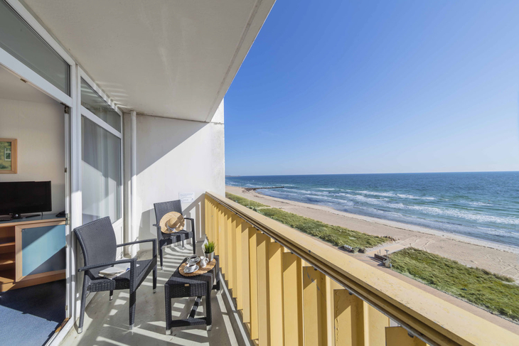 Balkon mit Blick auf die Ostsee und Sandstrand bei sonnigem Wetter.