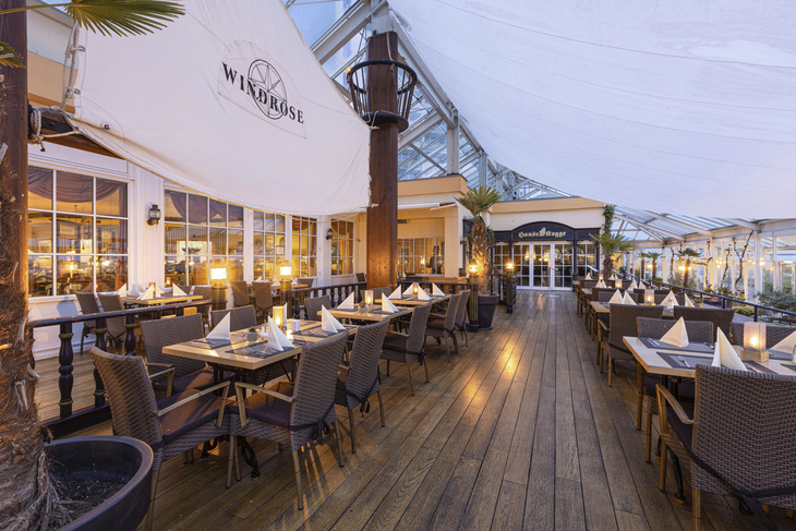 Außenbereich des Windrose Restaurants im IFA Fehmarn Hotel mit gedeckten Tischen.