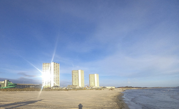 Hochhäuser am Strand von Fehmarn bei blauem Himmel und Meer.