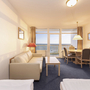 Ein gemütliches Hotelzimmer mit Sofa, Tisch und Blick auf das Meer.