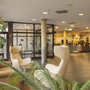 Hotel-Lobby mit Sitzbereich, Pflanzen und Rezeption im Hintergrund.
