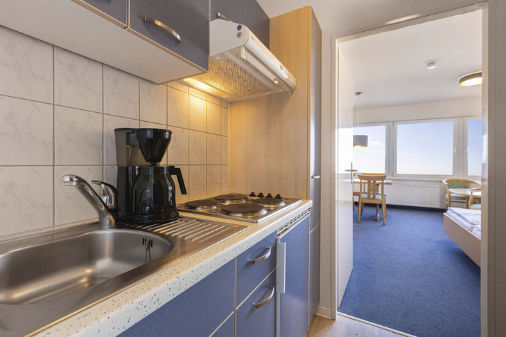 Kleine Küchenzeile in einer Ferienwohnung mit Blick in den Wohnbereich.