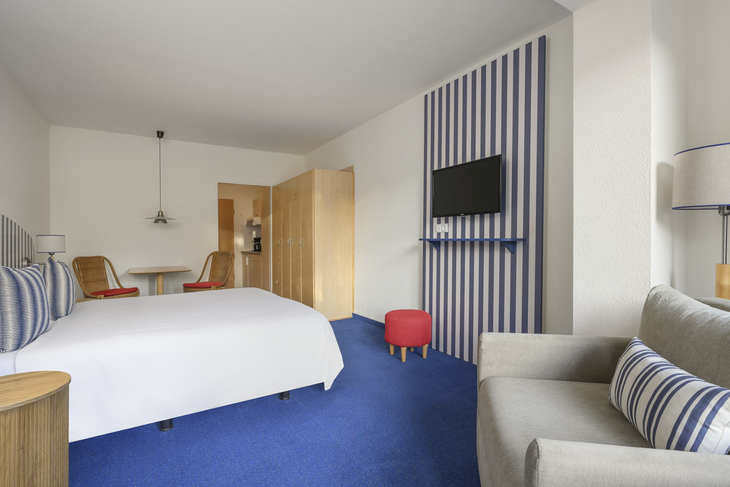 Helles Ferienwohnzimmer mit Bett, Sofa, TV und Esstisch in Binz auf Rügen.