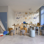 Kinderclubraum mit Spielzeug, Tischen und bunten Hockern.