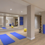 Moderner Fitnessraum mit blauen Matten, Fitnessbällen und Spiegelwand.