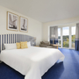 Modernes Hotelzimmer mit Doppelbett, blauen Streifen und großem Fenster.