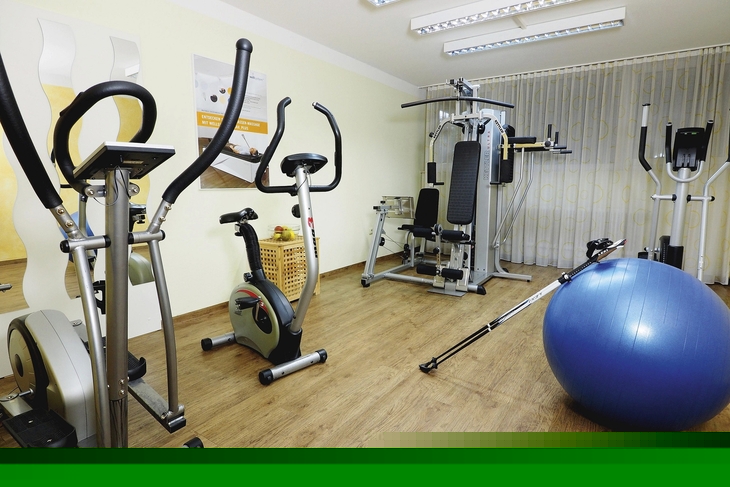 Fitnessraum mit Trainingsgeräten und einem großen blauen Gymnastikball.