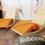 Zwei Liegestühle mit orangen Decken in Ruhebereich, Fokus auf Stein mit 
