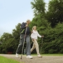 Zwei Personen beim Nordic Walking auf einem Weg im Grünen.