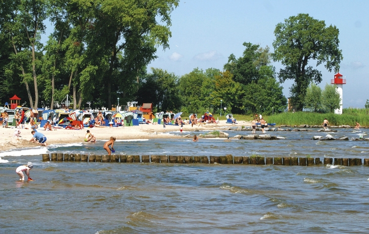 Strand mit Menschen und Leuchtturm bei Lagunenstadt Ueckermünde.