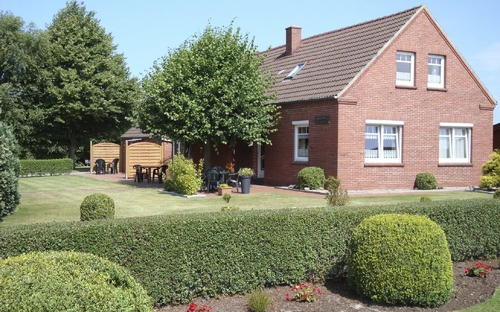 Rotes Backsteinhaus mit gepflegtem Garten und Terrasse.