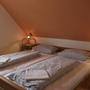 Doppelbett in gemütlichem Ferienwohnungsschlafzimmer mit Dachschräge.