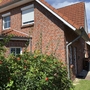 Ein rotes Ziegelhaus mit Garten, blauer Himmel im Hintergrund.