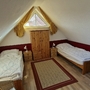 Dachzimmer mit zwei Einzelbetten, gelben Vorhängen und Holzmöbeln.