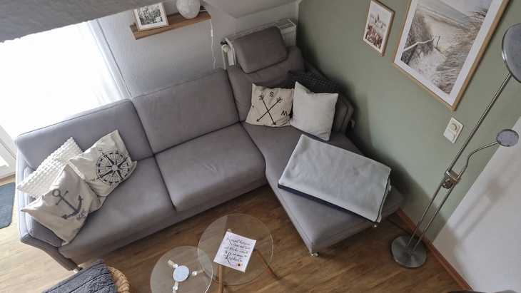 Graues Sofa mit maritimen Kissen in einer gemütlichen Ecke eines Wohnzimmers.