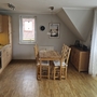 Küche und Essbereich mit Holztisch, Stühlen, Küchenzeile und großen Fenstern.