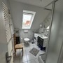 Badezimmer mit Dachfenster, Waschmaschine, Waschbecken und Dusche.
