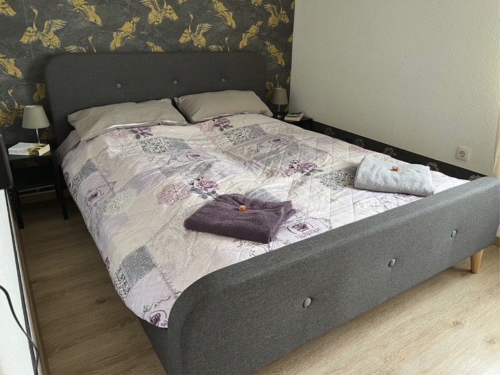 Doppelbett mit bunter Bettwäsche und Handtüchern in einem Schlafzimmer.