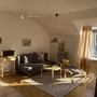Wohnzimmer mit Sofa, Sesseln und Balkonfenster in sonnigem Ambiente.