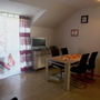 Wohnzimmer mit Tisch, Stühlen, Fernseher, gedecktem Tisch und Vorhang mit Schmetterling.
