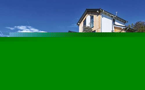 Ferienhaus in ländlicher Umgebung mit Garten und blauem Himmel im Hintergrund