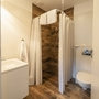 Badezimmer mit Dusche, WC und Waschbecken in modernem Bungalow.