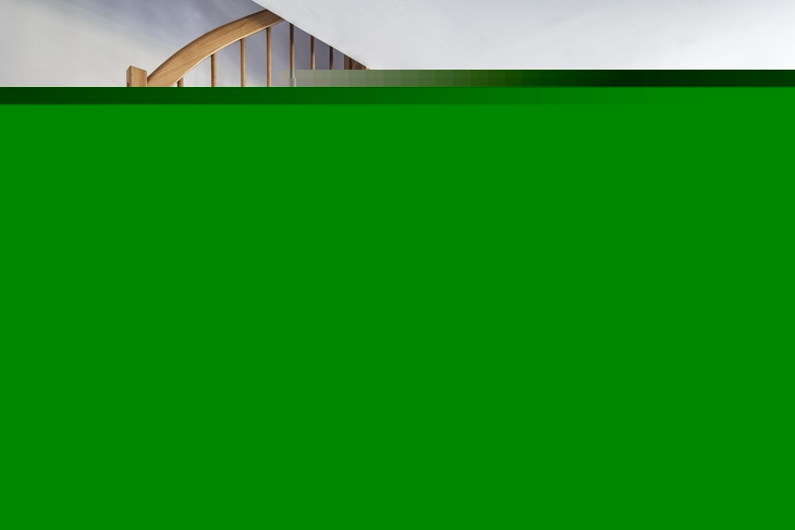 Wohnbereich mit Treppe, Sitzecke, großer Fensterfront und Blick ins Grüne.