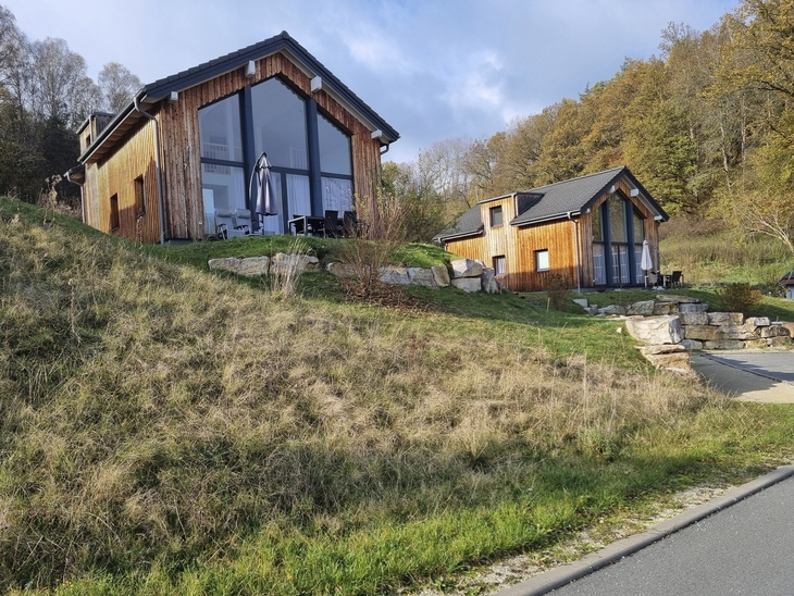 Holzchalets auf einem Hügel mit Terrasse, umgeben von herbstlicher Landschaft