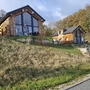 Holzchalets auf einem Hügel mit Terrasse, umgeben von herbstlicher Landschaft