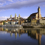Außenansicht eines Hotels am Flussufer mit Stadt im Hintergrund.