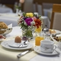 Frühstückstisch mit Brötchen, Blumenstrauß und Saft in einem Hotelrestaurant.