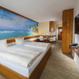 Modernes Gästehaus-Appartement mit Doppelbett, Meer-Wandbild, Holzmöbeln und TV.